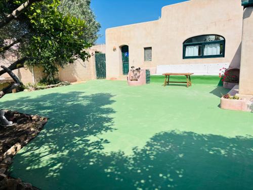 a green yard with a picnic table and a building at Villa Turquoise Formentera in San Ferrán de ses Roques