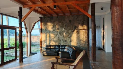 a living room with a leather couch and a stone wall at Lakeside Echo Homestay in Kurunegala
