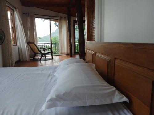 a bedroom with a bed with a wooden headboard and a window at Lakeside Echo Homestay in Kurunegala