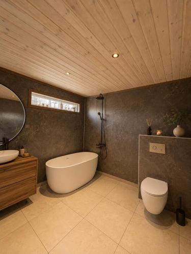a bathroom with a tub and a toilet and a sink at Jarfjord Nature Escape in Herjenes