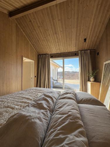 a large bed in a room with a large window at Jarfjord Nature Escape in Herjenes