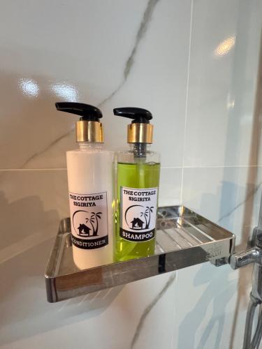 two bottles of soap sitting on a shelf in a bathroom at The Cottage Sigiriya in Sigiriya