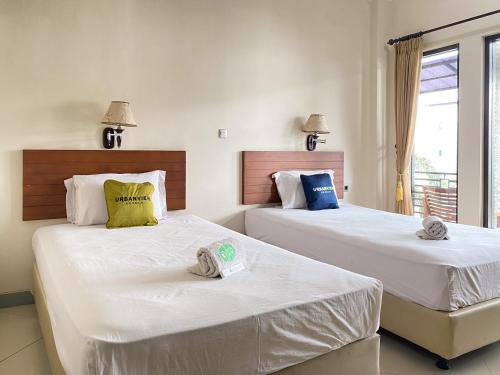 two beds in a hotel room with towels on them at Urbanview Hotel Ratna Syariah in Sukobumi