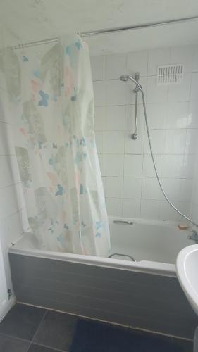 a bathroom with a bath tub with a shower curtain at Wigston house in Wigston Magna