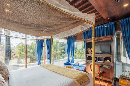 a bedroom with a canopy bed with blue curtains at Le Dupleix in Pondicherry