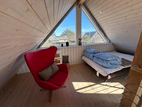 a room with a red chair and a bed and a window at Guesthouse Villa Sønderklit in Skagen