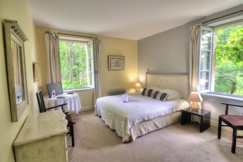 a bedroom with a large bed and two windows at Logis Hôtel Le Moulin de la Beune in Les Eyzies-de-Tayac