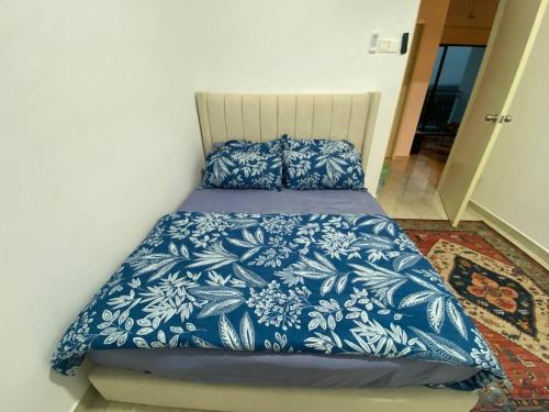 a bed with blue and white sheets and pillows at Riverfront Homestay at Ambience Residence in Malacca