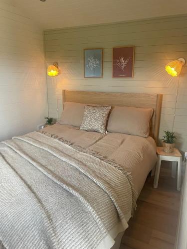 a large bed in a bedroom with two lights at Hillhouse Coastal Escapes - PODs in Donegal