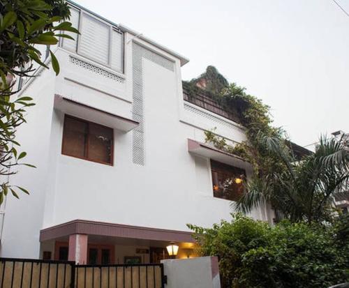 een wit gebouw met een hek ervoor bij Frangipani Penthouse in New Delhi
