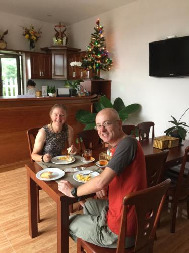 a man and a woman sitting at a table with food at Tra Que Riverside Homestay in Hoi An