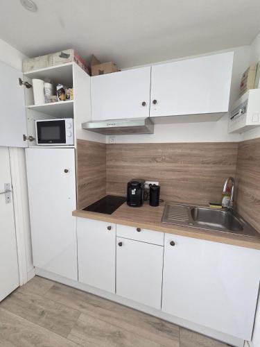 a kitchen with white cabinets and a sink at La Parenthèse, studio in Gruissan