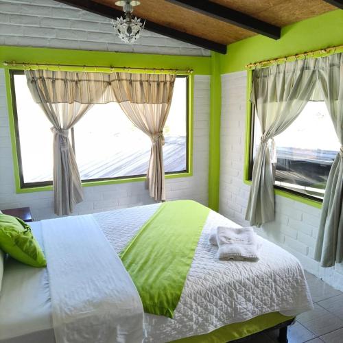 a bedroom with a bed and two windows at Hostería Agoyán Deluxe in Ulba