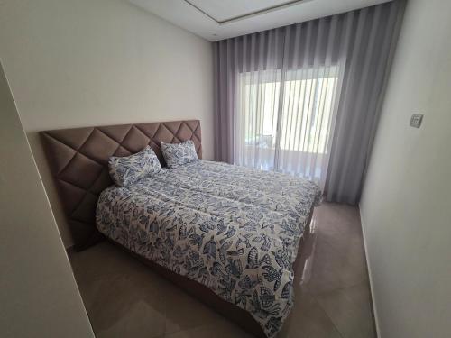 a bedroom with a bed and a large window at Cozy apartment with pool view in Dar Hamida