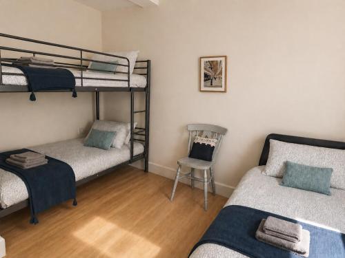 a room with three bunk beds and a chair at Steam Mill in Wellow