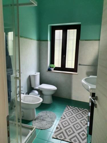 a green bathroom with a toilet and a sink at Appartamento - Plemmirio - Villa Maria Serena in Syracuse