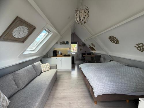 a attic bedroom with a bed and a couch at Logeren op Dijk43 in Broek op Langedijk