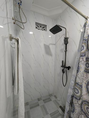 a bathroom with white marble walls and a shower at WAB STAR Lodge in Kumasi