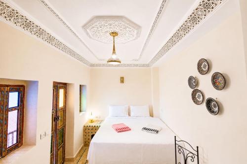 a white bedroom with a bed and plates on the ceiling at Riad Medina Unique in Fez