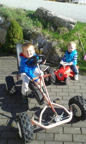 two young boys riding on a toy four wheeler at Apartment Bauernhof Thurnummerstall in Hollersbach im Pinzgau