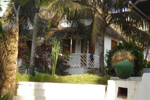 a white house with palm trees in front of it at Hotel La Caravelle in Ambatoloaka
