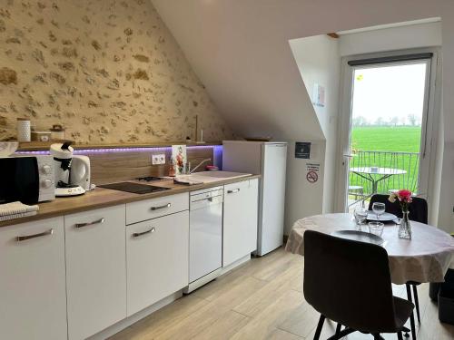 a kitchen with white cabinets and a table with a tableablish at Séjour à la campagne - Logement cosy et chaleureux in Courgains