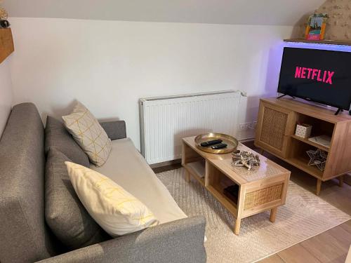 a living room with a couch and a tv at Séjour à la campagne - Logement cosy et chaleureux in Courgains