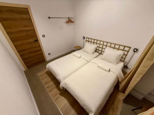 a bedroom with a bed with white sheets and a door at The Orange Teddy Bear Gijón in Gijón