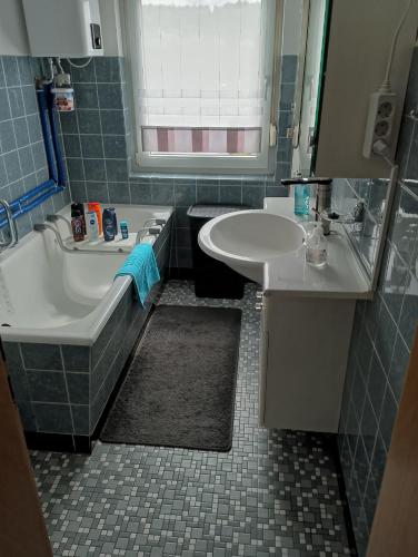a bathroom with a sink and a tub and a sink and a mirror at Ferienwohnung Jahnke in Burkardroth