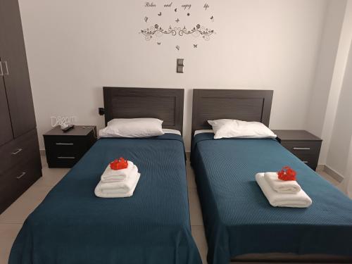 two beds in a room with blue sheets and red roses at Levanda House in Palekastron