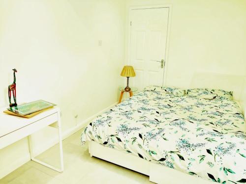 a white bedroom with a bed and a table and a lamp at New Studio Near Science Park Cambridge in Cambridge