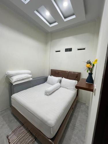 a bedroom with a bed with white sheets and a table at Nok Homestay in Pangururan