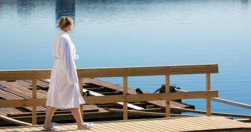 a woman walking on a dock near the water at Finlandia Hotel Alba in Jyväskylä