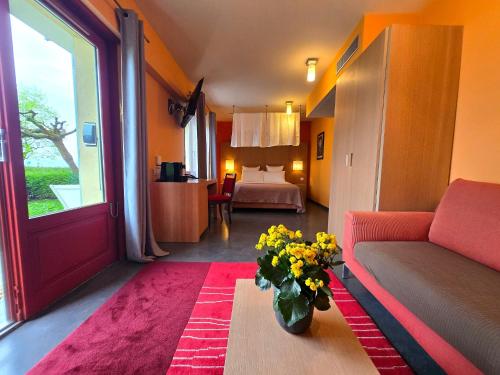 a living room with a couch and a vase of flowers at Hôtel La Riviera Victoria in Yvoire