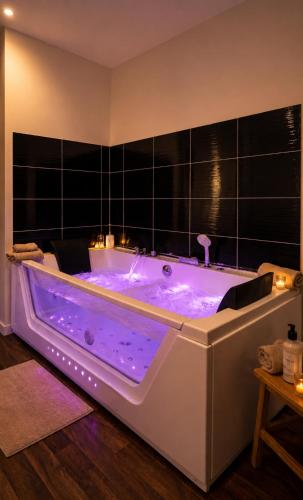 a bath tub with purple lighting in a room at Loft Spa lumineux Jacuzzi privé écran cinéma in Roubaix