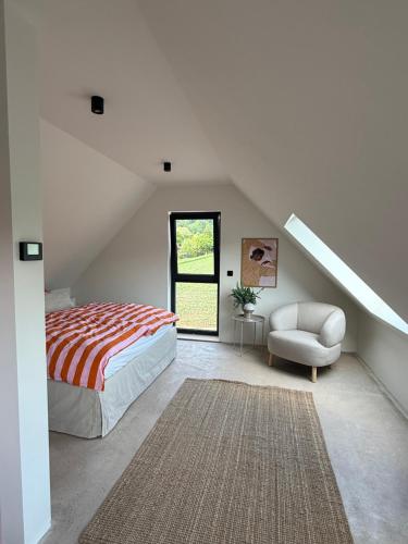 a bedroom with a bed and a chair and a window at Modernes Tinyhouse im Weserbergland nahe Hameln in Hessisch Oldendorf