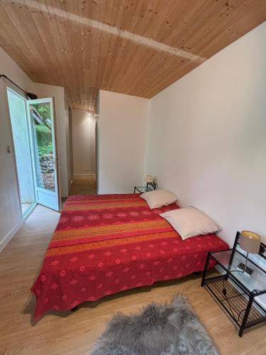 a bedroom with a large red bed with a wooden ceiling at La Petite Ferme des Etoiles in Mauroux