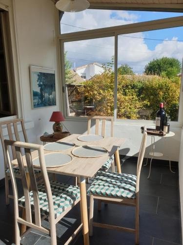 a wooden table and chairs in a room with a window at La Flibuste in Andernos-les-Bains