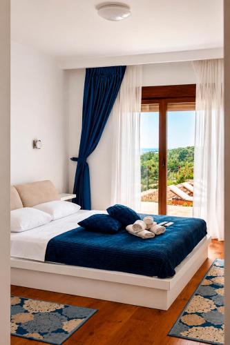 a bedroom with a bed with blue sheets and a window at Villa Vitanika in Kunjići