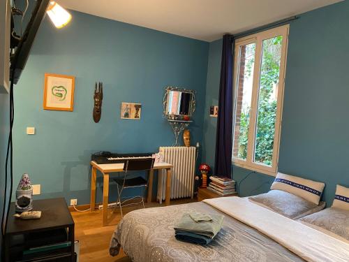 a bedroom with a bed and a desk with a piano at Chambre chez l'habitant dans grande maison Arborée in Orly