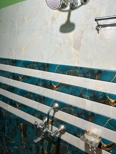a bathroom with a shower with blue and white tiles at Snehalata Lodge in Badarpur
