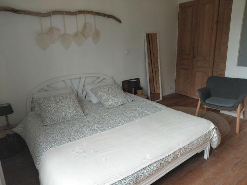 a bedroom with a white bed and a blue chair at La Canardière in Pendé