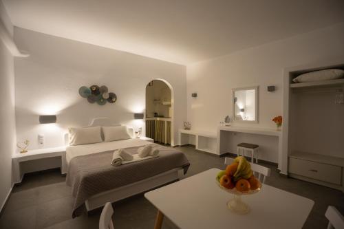 a white bedroom with a bed and a table at Galaxy studios in Astypalaia
