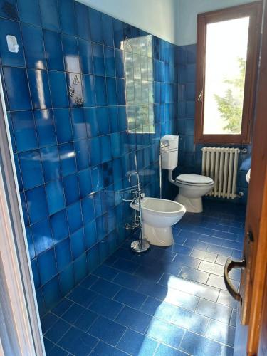 a blue tiled bathroom with two toilets and a window at B&B Pizziconi Relax in Podere Modello