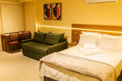 a hotel room with a bed and a green chair at Loft moderno e aconchegante no coração de Icaraí in Niterói