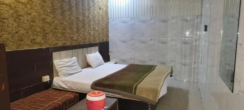 a small bedroom with a bed and a bench at Hotel Shyam in Agra