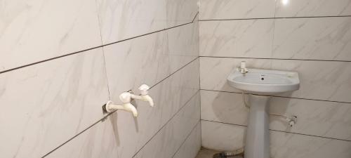a white bathroom with a sink and a toilet at Hotel Shyam in Agra
