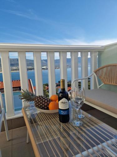 a table with a bottle of wine and fruit on a balcony at Compass Apartment in Trogir