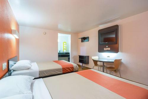 a hotel room with two beds and a table and a tv at Motel 6-Round Rock, TX in Round Rock