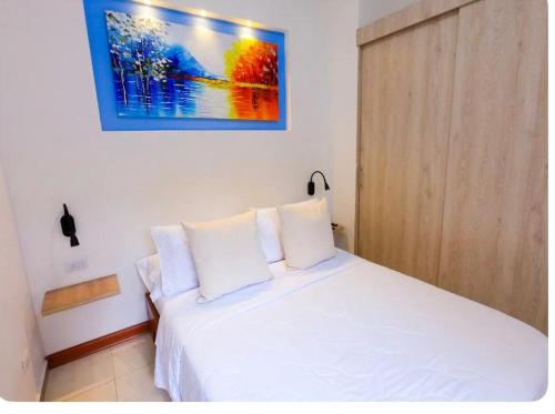 a bedroom with a white bed and a painting on the wall at Descanso y confort in La Tebaida